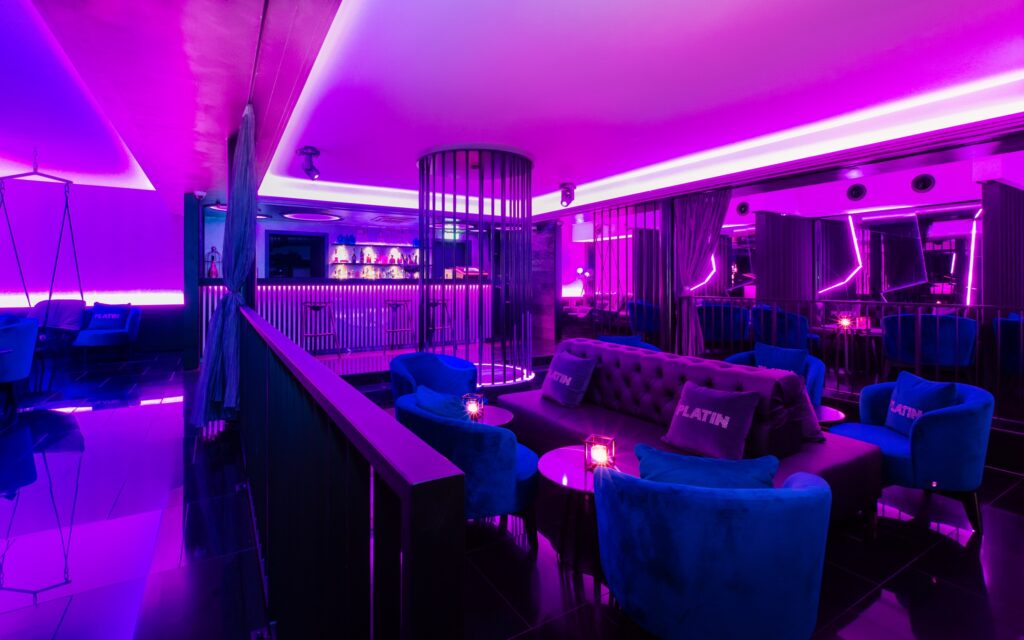 PLATIN Lounge mit blauen Sesseln im Magentalicht