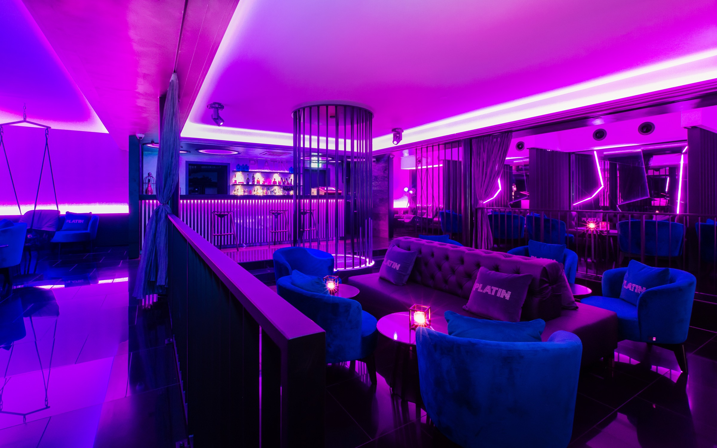PLATIN Lounge mit blauen Sesseln im Magentalicht